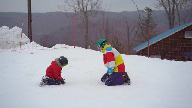 A young man and his little son have fun on a ski slope in a mountain resort activities park. Winter holidays concept. SLowmotion shot.