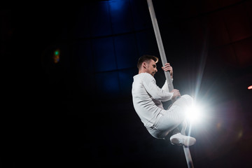 back light near strong acrobat performing on metallic pole
