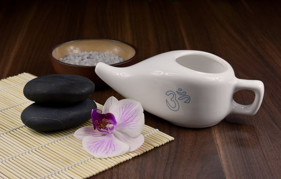 Ceramic Neti pot for nasal cleansing stock images. White ceramic Neti pot with OM symbol. Neti pot still life with zen stones and orchid flower stock images. White Neti pot on a wooden background