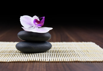 Massage stones with orchid stock images. Spa and wellness setting stock images. Pile of black stones. Black stones on a wooden background. Spa-concept with zen stones and orchid flower stock images
