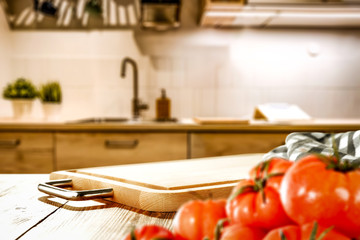 Kitchen vegetable chopping board with space for your product. Interior of fuzzy Italian kitchen furniture. White light from the lamp. Fresh vegetables and fruits.