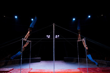 four gymnasts performing on horizontal bars in arena of circus © LIGHTFIELD STUDIOS
