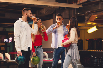 Group of friends drinking beer in a bowling alley