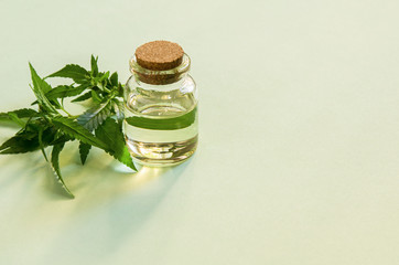 Cannabis green fresh leaves close-up and oil in bottle on paper background. Hemp grass plant foliage for medicine, copy space