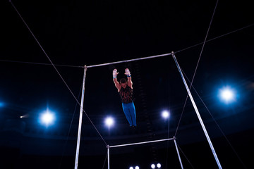 athletic gymnast jumping while performing on horizontal bars in arena of circus © LIGHTFIELD STUDIOS