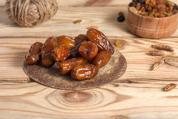 Tasty dates on a round substrate close-up on a wooden background
