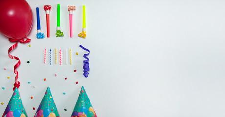 The concept of birthday. The frame is made of confetti and streamers, cone-shaped caps, blowouts, cake candles and balloon on a white background. Free space