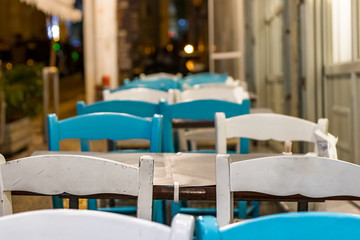 Wooden chairs and table outdoors on the street of a greek taverna.