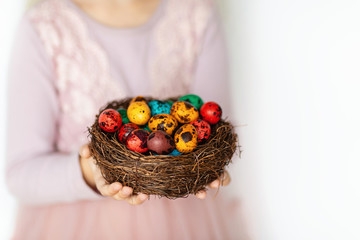 Fototapeta na wymiar Cute little girl holding nest with Easter eggs on white background. Adorable child celebrate Easter holiday