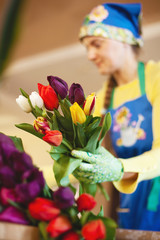 Girl florist is packing beautiful tulips in a flower shop in kraft paper. Women's Day and Valentine's Day