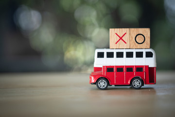 Wooden block of X O on red school bus