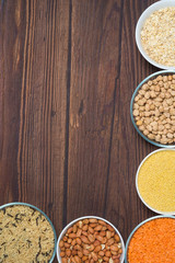 grains red lentils, basmati rice, buckwheat, chickpeas, millet in plates. organic healthy cereals. on a wooden background. natural vegetarian vegetable protein . the view from the top. vertical frame