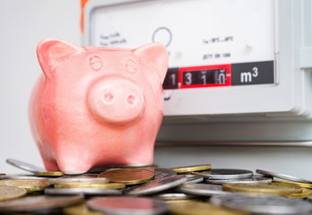 Piggy bank and coins near the natural gas meter at home. Symbolic image of a payment for heating in...