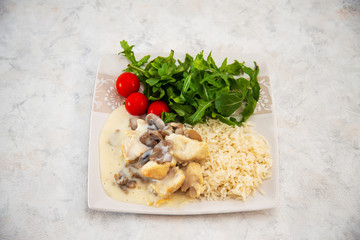 Pieces of chicken fillet cooked in a cream sauce with mushrooms and lemon juice, served with rice.