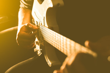 Man playing electric guitar in the shadow. Musical instrument photo. Musician under the spotlight....