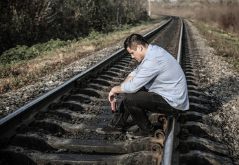 Man with alcohol on railway tracks outdoors. Travel concept. Lonely person. Suicide concept. Depression disease.