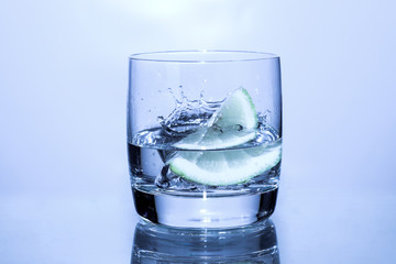 glass of water with lemon or lime on blue background