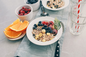 Healthy breakfast: oatmeal with  raspberries,oranges and blueberries. Homemade granola. Healthy breakfast ingredients. Bowl of oat granola with milk, fresh fruit. Top view, copy space