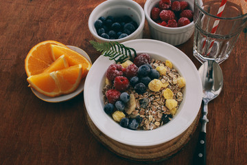 Healthy breakfast: oatmeal with  raspberries,oranges and blueberries. Homemade granola. Healthy breakfast ingredients. Bowl of oat granola with milk, fresh fruit. Top view, copy space