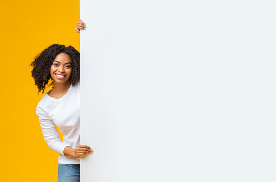 Cheerful afro woman holding big white advertisement board with free space