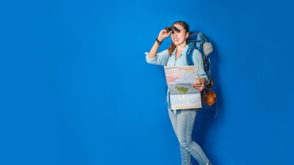 Young asian traveler happy woman in Blue shirt with backpack with and equipment for travelers Vacation with a map, on Blue color background. Travel backpack