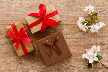 Gift boxes with cherry flowers on the wooden background.