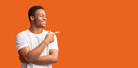 Young black man pointing at copy space with thumb up