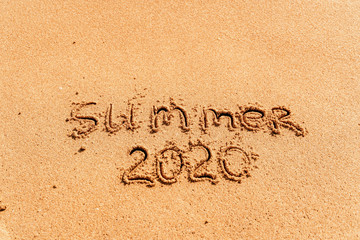 2020 summer lettering on the beach with wave and clear blue sea. Travelling on summer vacation