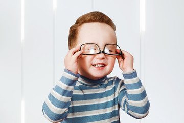 Smiling baby boy dresses glasses. Cute little infant boy is playing with sunglasses, wearing them...