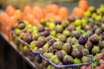 Purple and green ripe figs in plastic baskets, on a blurred background. For sale in the fruit market, Jerusalem.