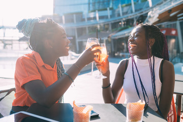 Two beautiful black women sisters making a toast doing happy hour - enjoying, happiness,...