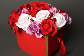 Flowers in bloom: Bouquet of red and white roses in a red box on a gray background.