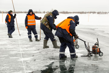 Workers cut ice blocks to the size of ice on a frozen lake