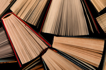 Naklejka premium Books. Lots of colourful thick open books stand on a dark background
