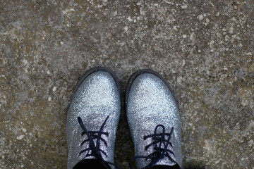 Unrecognizable person wearing silver glittery shoes. Selective focus. 