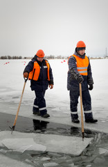 Workers rafting ice blocks along a channel cut out by a frozen lake