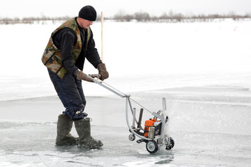 Worker cuts out ice blocks in size on the ice of a frozen lake