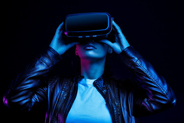 African american girl in vr glasses, watching 360 degree video with virtual reality headset isolated on black background, illuminated by neon lights
