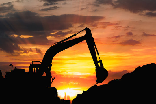  Silhouette of excavator loader  in the construction site on the sky sunset with cityscapes background
