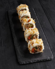 Traditional Asian dish sushi rolls on black slate plate