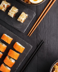 Traditional Asian cuisine sushi rolls and noodles on a black wooden table