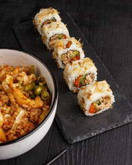 Traditional Asian cuisine sushi rolls and noodles on a black wooden table