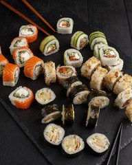 Traditional Asian dish sushi rolls on black slate plate