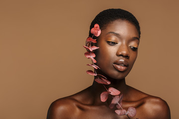 Beauty portrait of young half-naked african woman holding exotic flower
