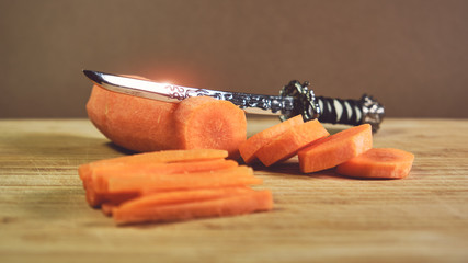 Fresh carrot chopped into slices and julienne strips with Japanese katana samurai sword
