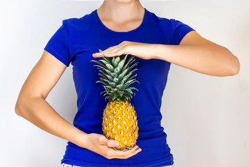 The person's body holds in hands a fruit pineapple against the background of the abdomen. Healthy...