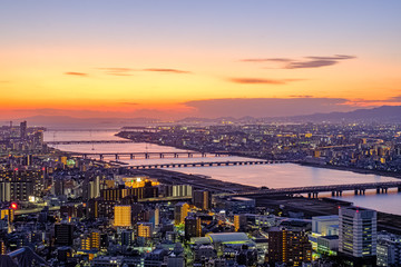 Obraz premium Aerial sunset view of Osaka skyline with the river, citylight, and golden sky as seen from Umeda Sky Building.