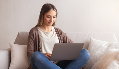 Naklejka premium Charming millennial girl typing on laptop at home