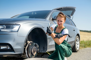 Woman in uniform working for car brake maintenance. Car repair. Safety work.