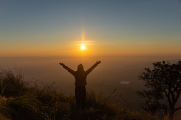 Fototapeta premium rear of happy woman stand on top mountain looking view with sunrise and mist at (Doi Norg Doi Luang National Park) Phayao province. soft focus.